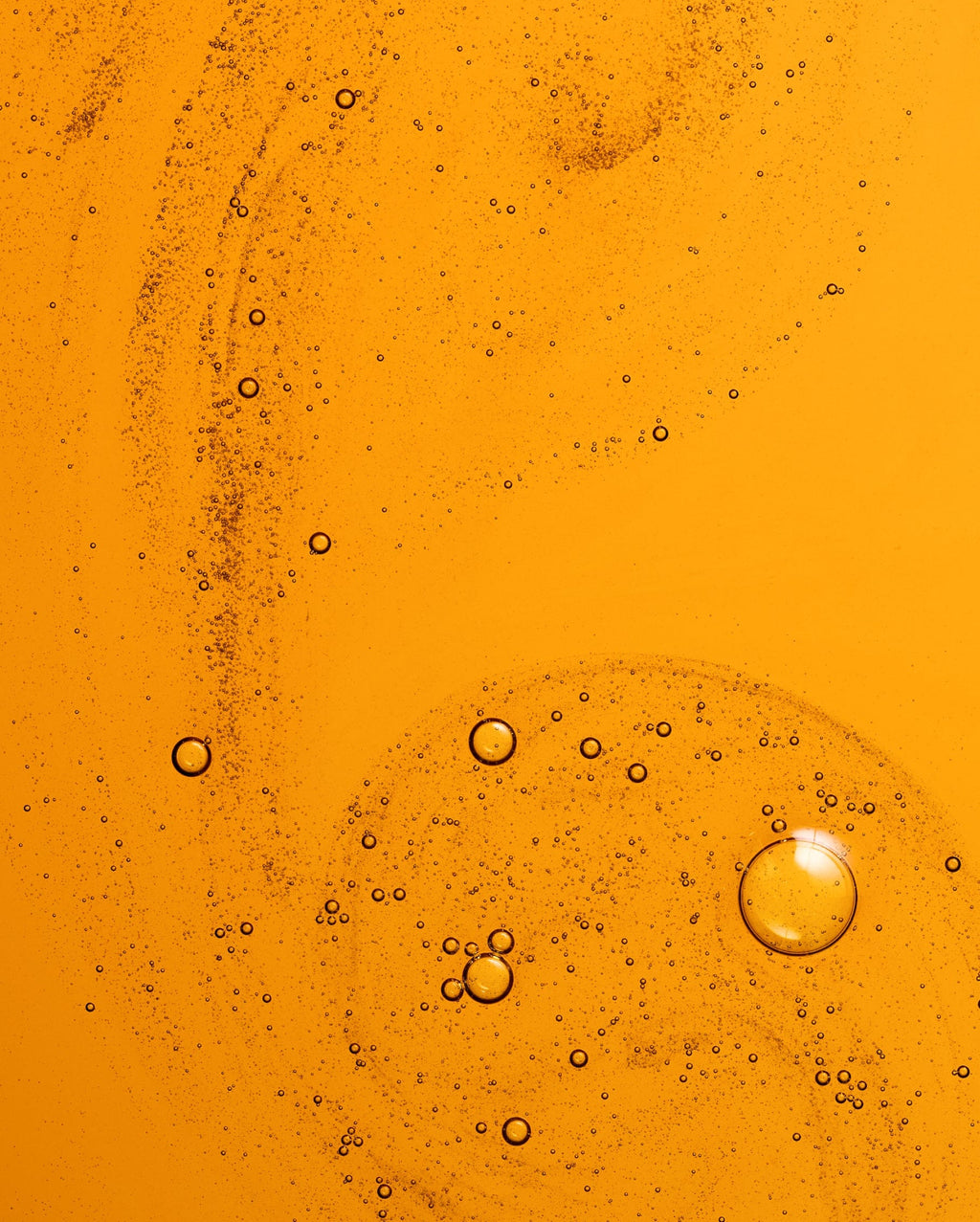 Bambu Earth 3% Bakuchiol Brightening Serum - Close-up of oil and water layers with bubbles on an orange background