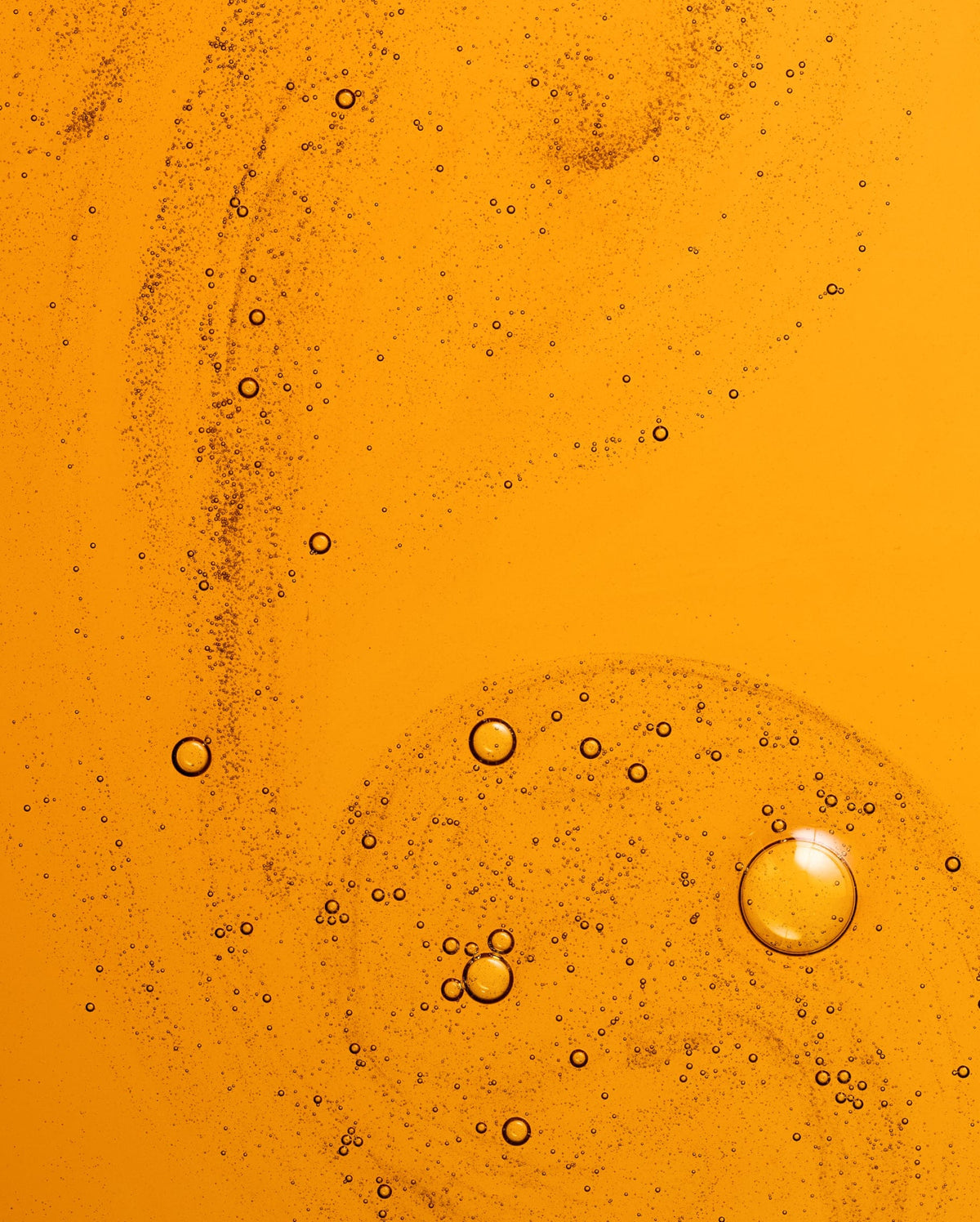 Bambu Earth 3% Bakuchiol Brightening Serum - Close-up of oil and water layers with bubbles on an orange background