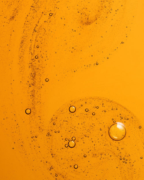 Bambu Earth 3% Bakuchiol Brightening Serum - Close-up of oil and water layers with bubbles on an orange background