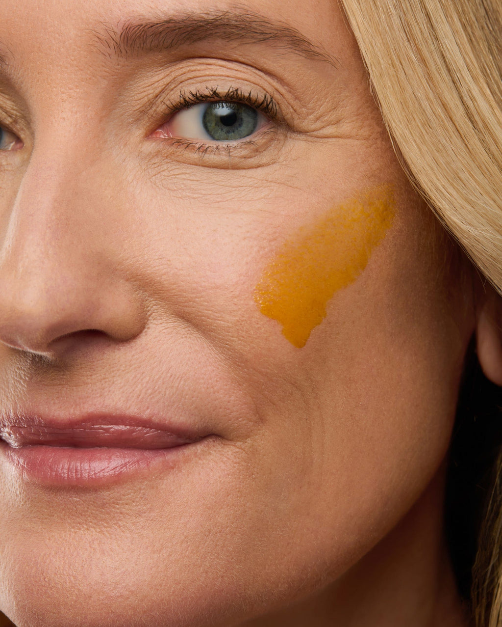 Bambu Earth 3% Bakuchiol Brightening Serum - Close-up of a woman's face with a yellow substance on her cheek