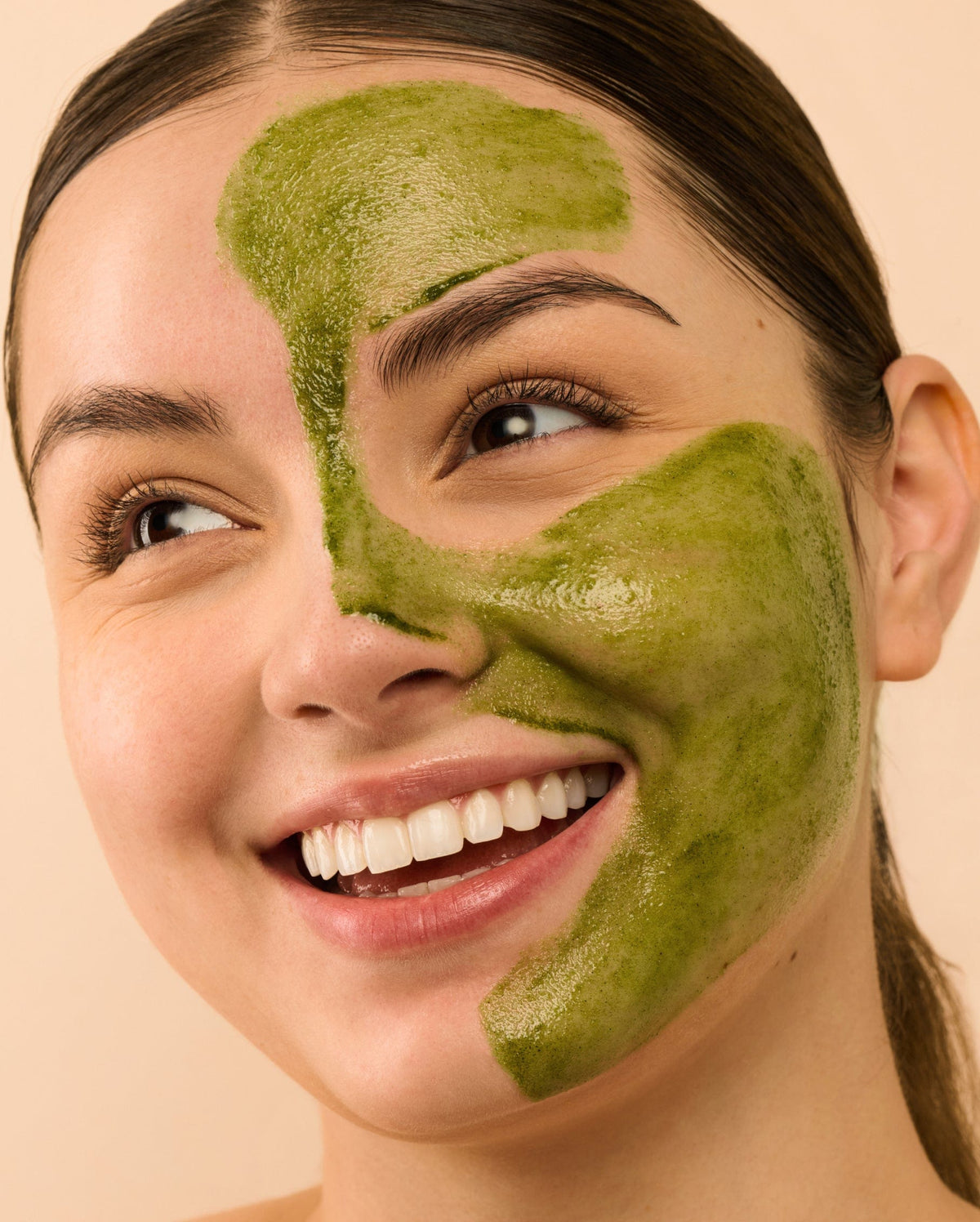 Bambu Earth Bambu + Willow Polishing Mask - Woman with green facial mask on half of her face against a beige background