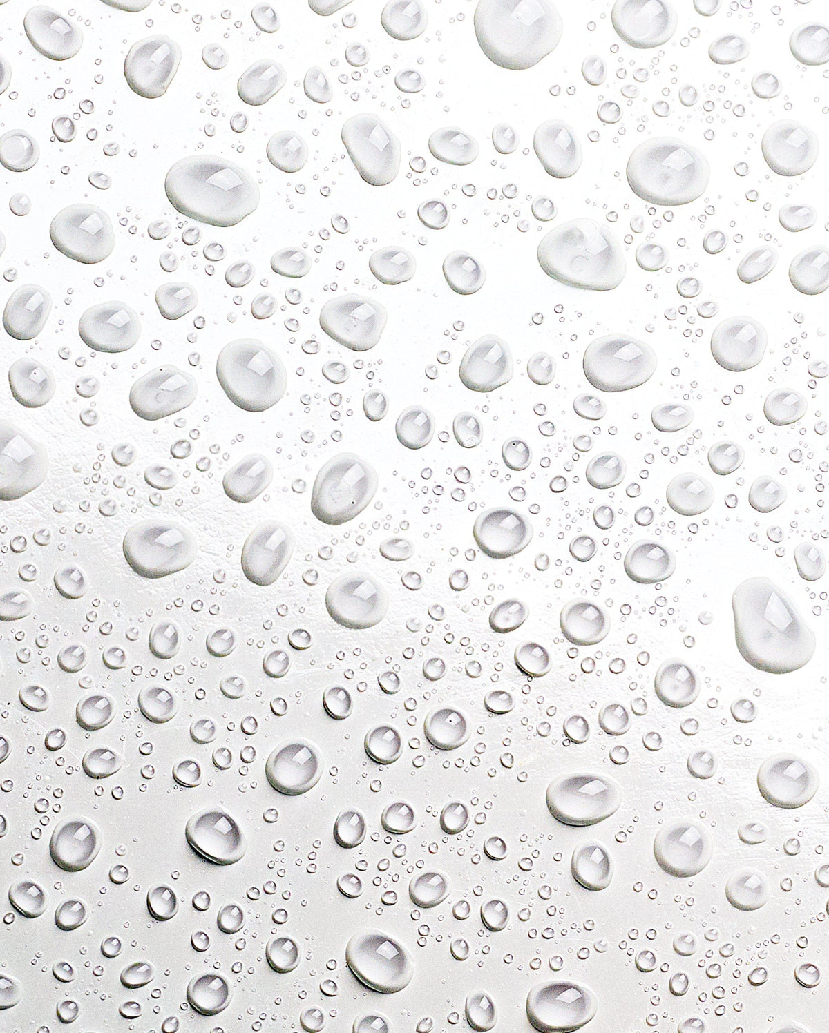Bambu Earth Helichrysum Hydration Facial Mist - Clear water droplets of varying sizes scattered across a glossy white