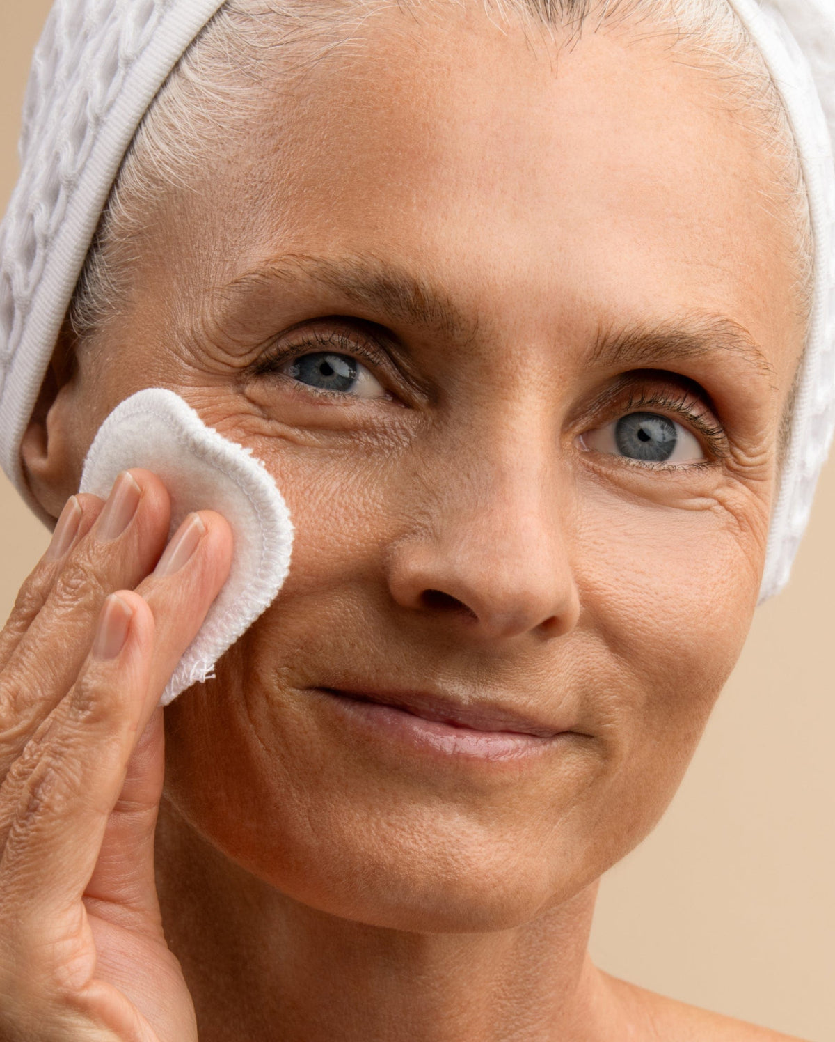 Bambu Earth Rosewater Cleanser - Woman cleaning her face with a white cloth against a beige background